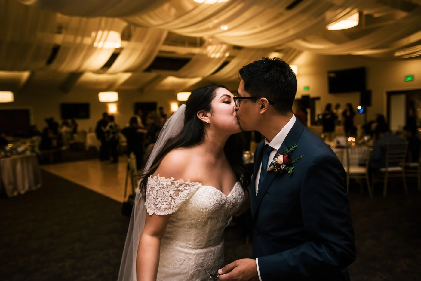 Couple kisses after their cake cutting at wedding reception.