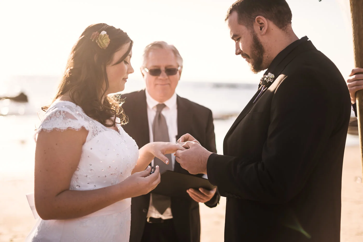 Couple exchanges wedding rings under the light of the setting sun on the sands of Laguna Beach.