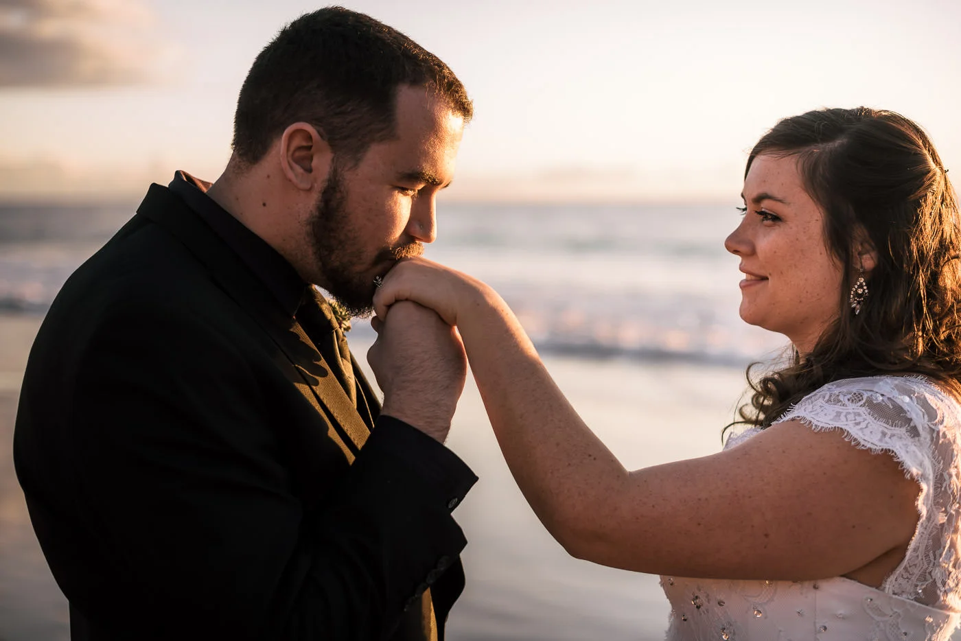 Groom gives the hand of his new wife a kiss as he admires her wedding ring.