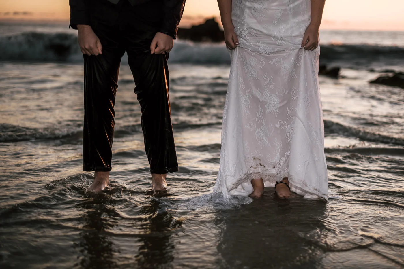 Couple shows off their bare feet as the tide rolls in.