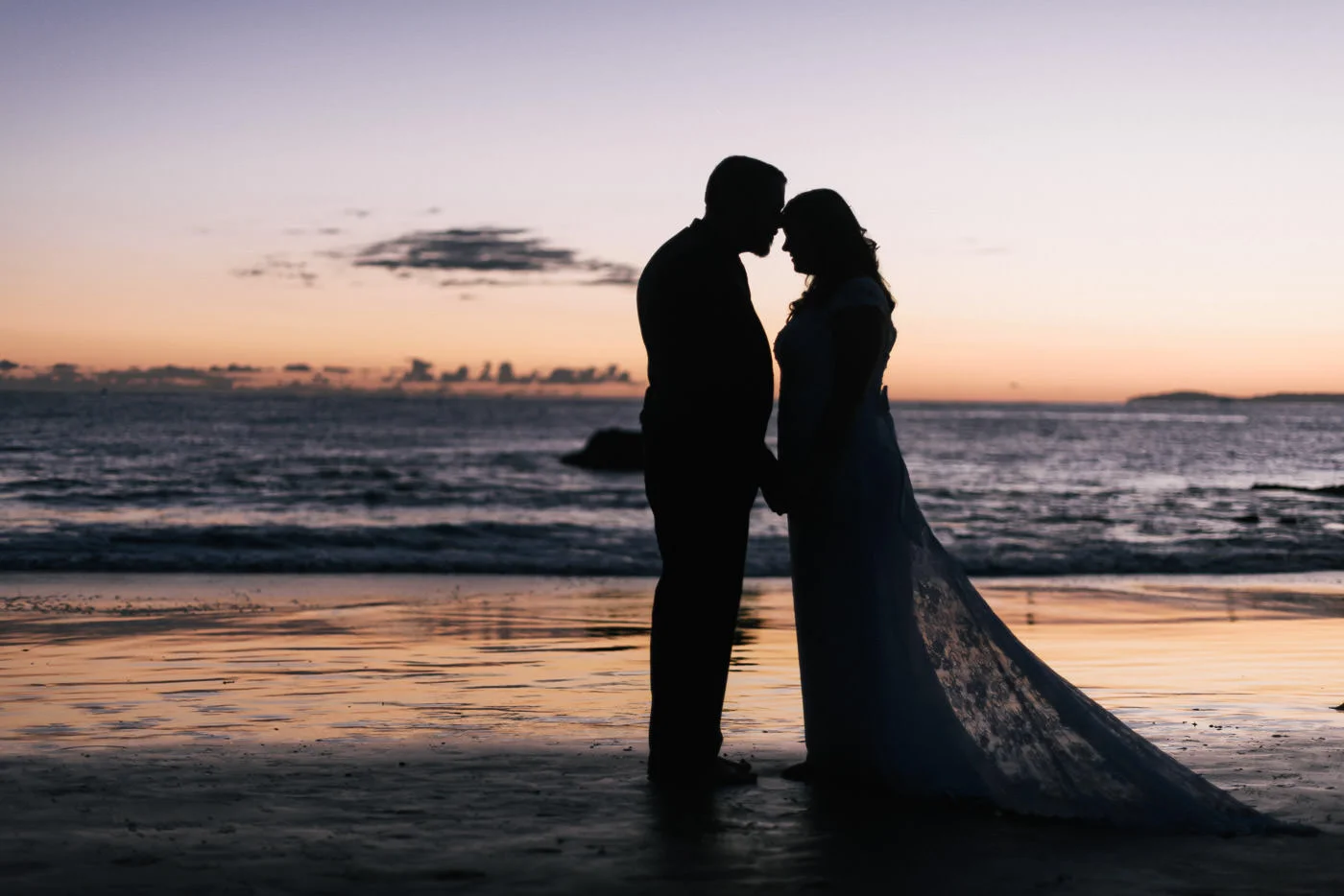 Sillhouetted couple gets close for a stunning wedding photo in Laguna Beach.