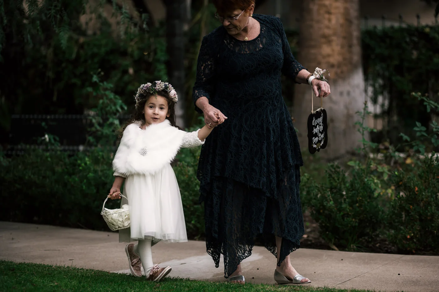 Adorable flower girl with faux fur shawl walks down the asile at Castle Green.