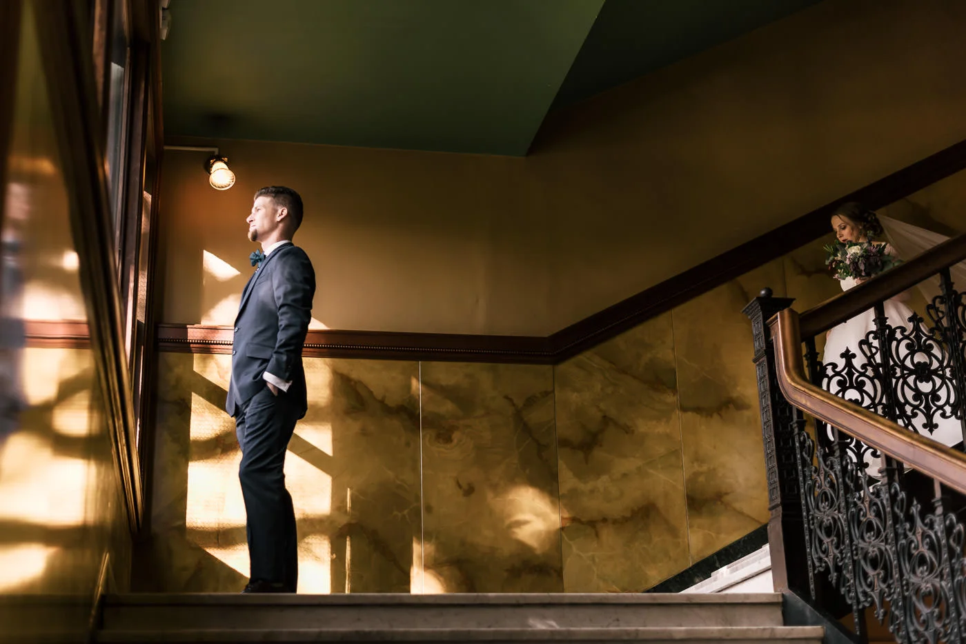 Bride decends staircase while the groom anxiously awaits their first look.