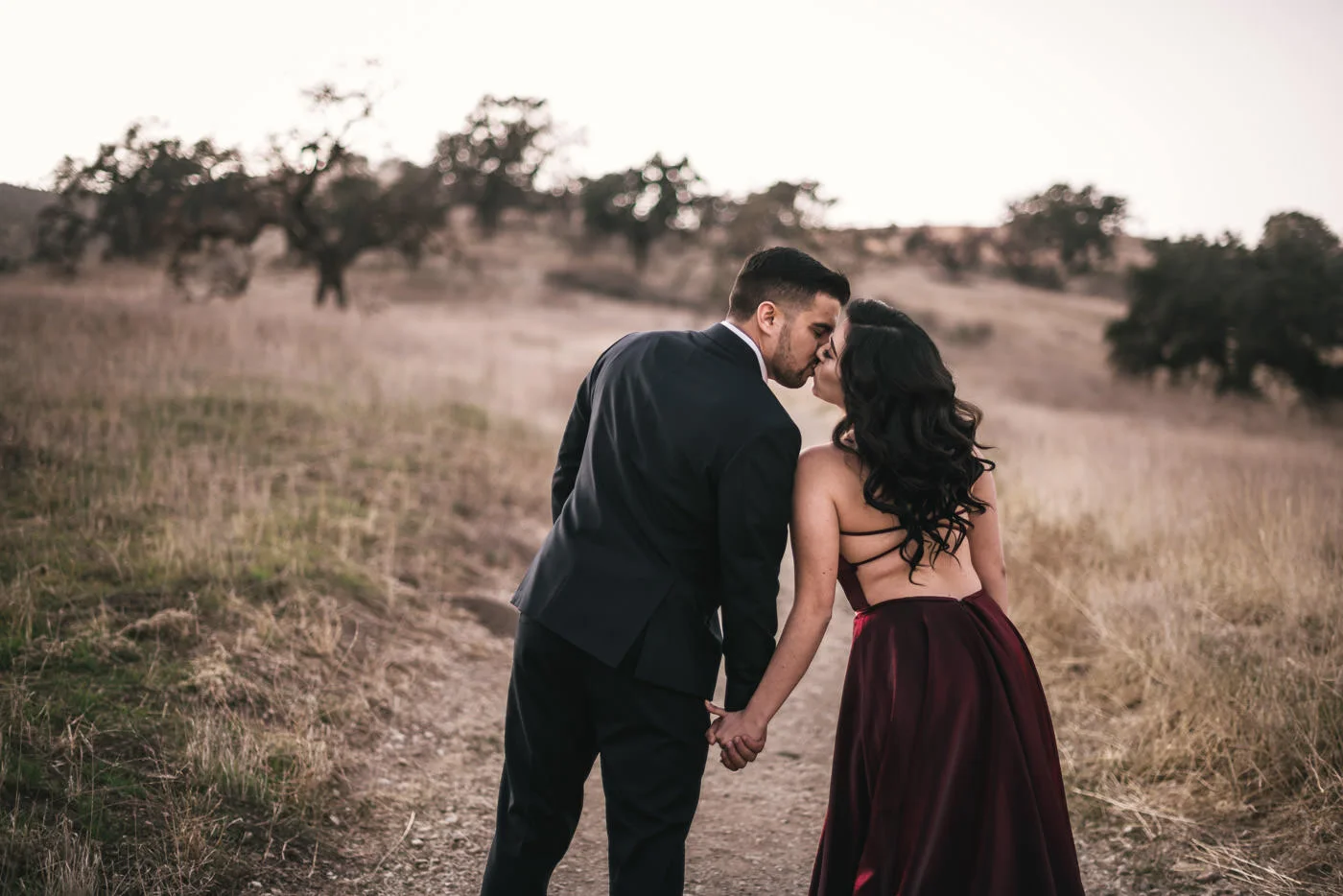 A pair of lovers stop to kiss as they stroll through the fields of Malibu.