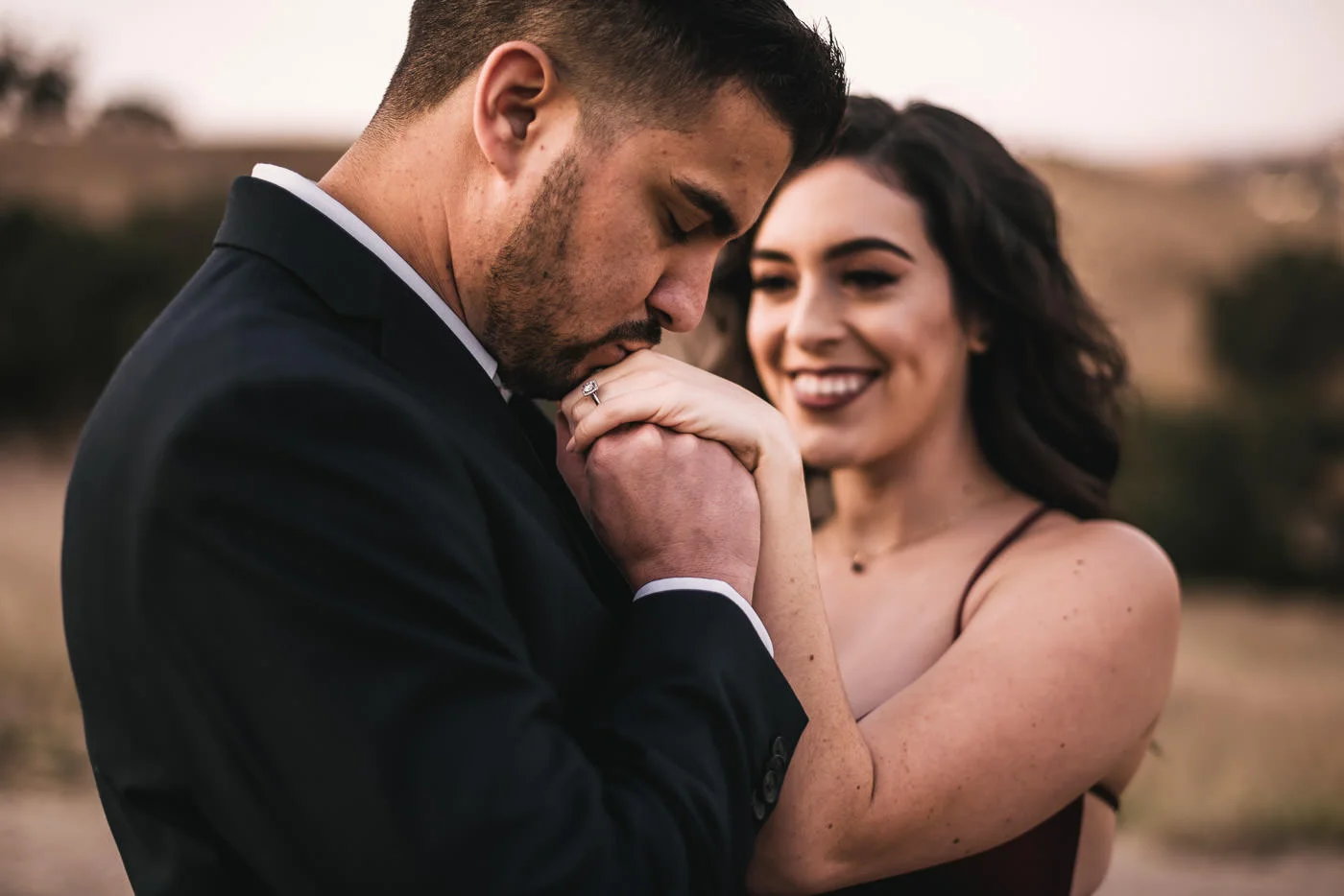 Groom gives his soon to be wife's hand a kiss to show off the engagement ring.