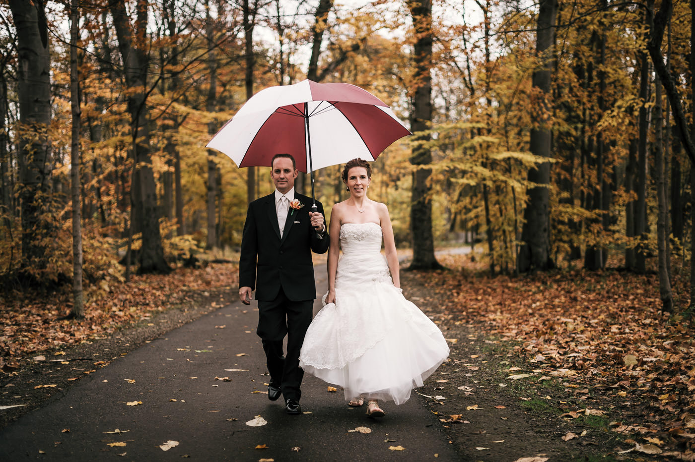 newlyweds takes a romantic walk through the woods after their michigan elopement in fall