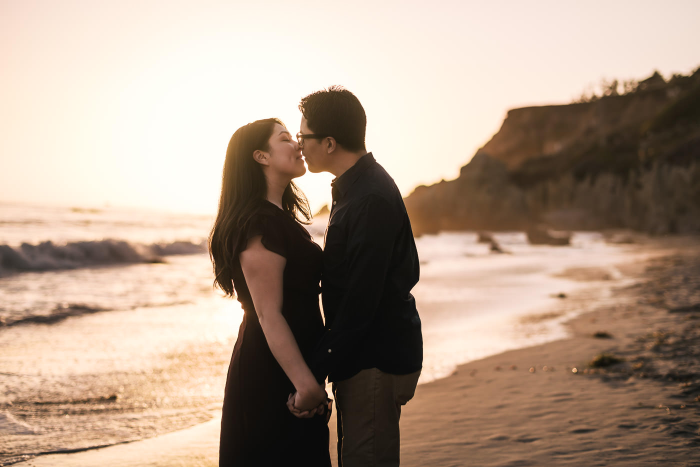 Heartfelt kiss on the beach in Malibu awash in the golden light of sunset.