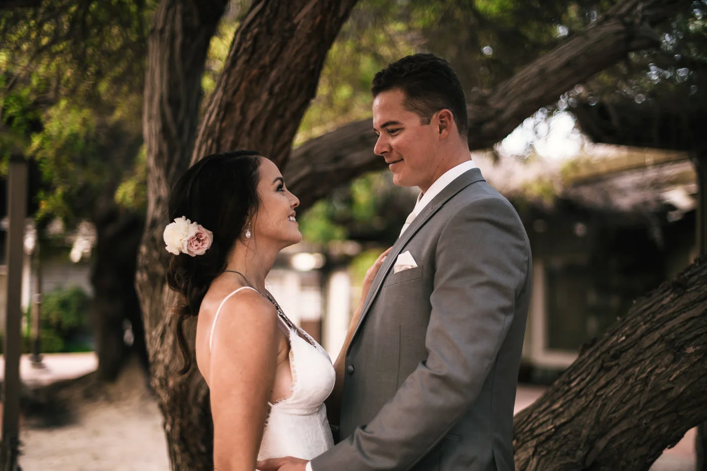 Bride and groom hold each other close as they stand in front of a twisting tree at Marina VIllage.