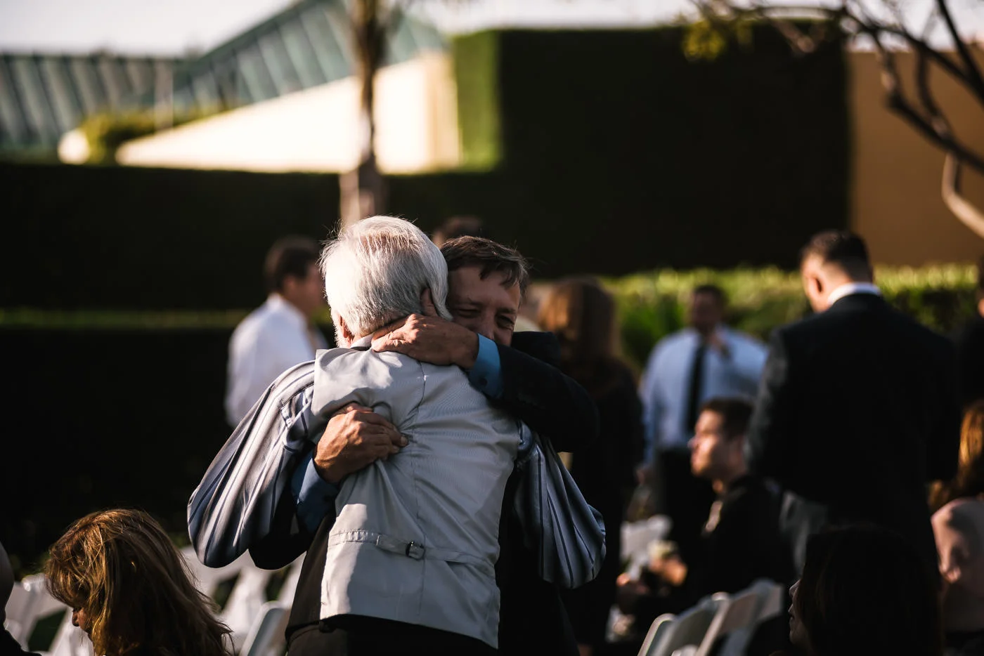 Father of the groom hugs a guest moments before the ceremony starts.