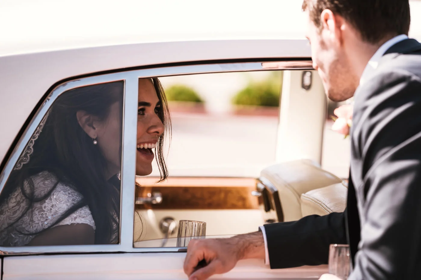 Groom chats with his new bride through the window of a classic Rolls Royce.