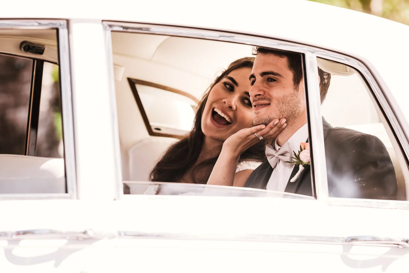 Playful bride laughs as she tenderly touches her husbands chin.