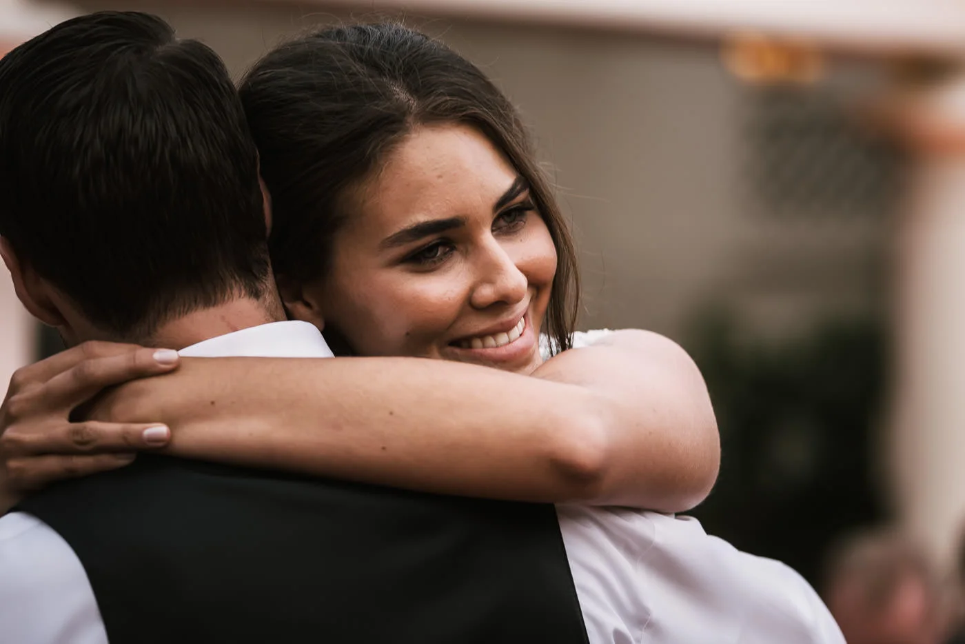 Newly married bride hugs her husband after their first dance.
