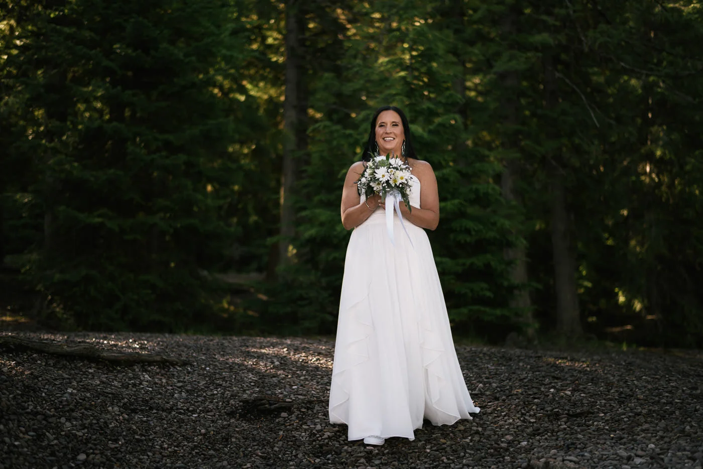 Bride is all smiles as she sees her new husband on the shores of Lake McDonald for their adventurous elopement.