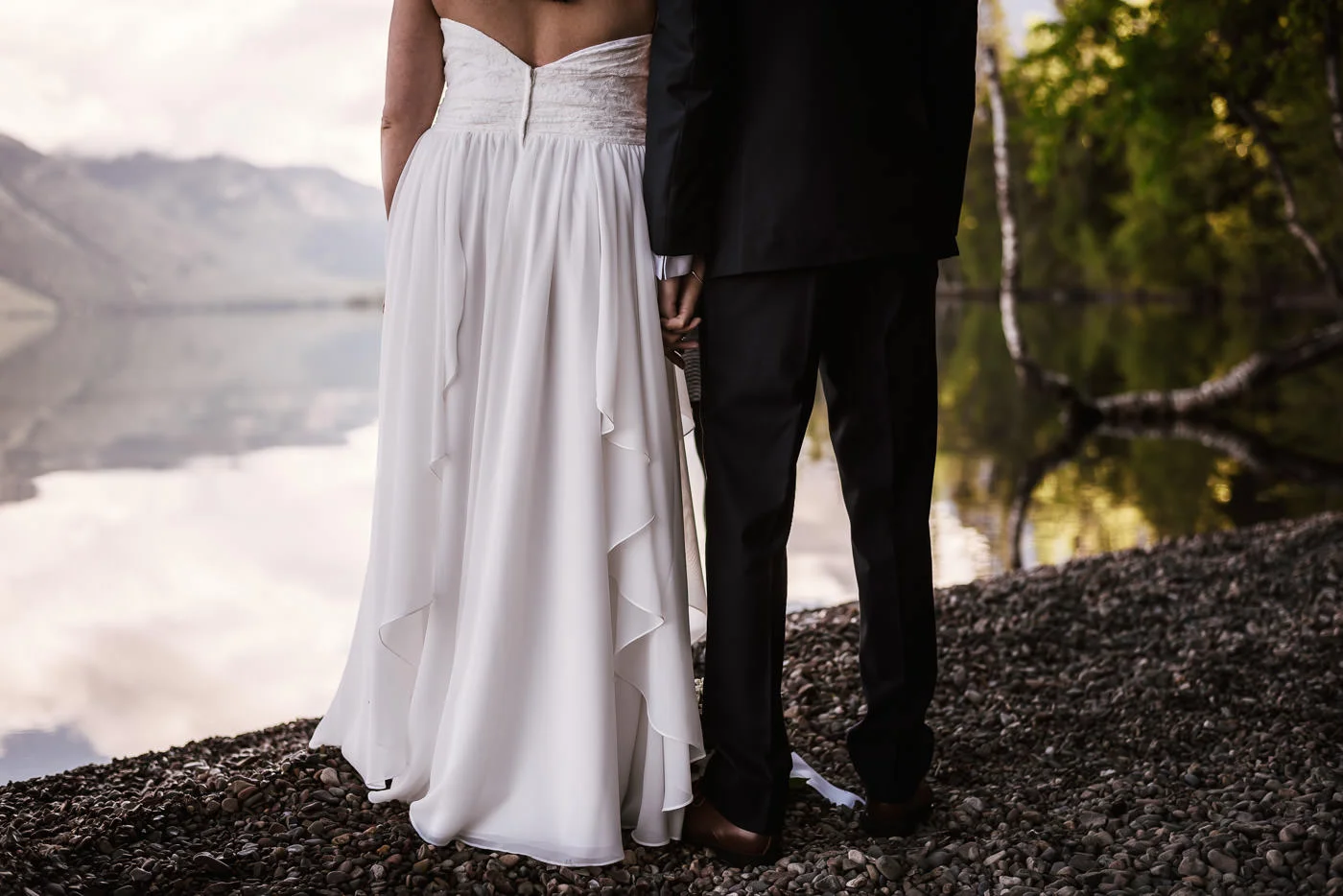 Couple holds hands and stare out over the lake.