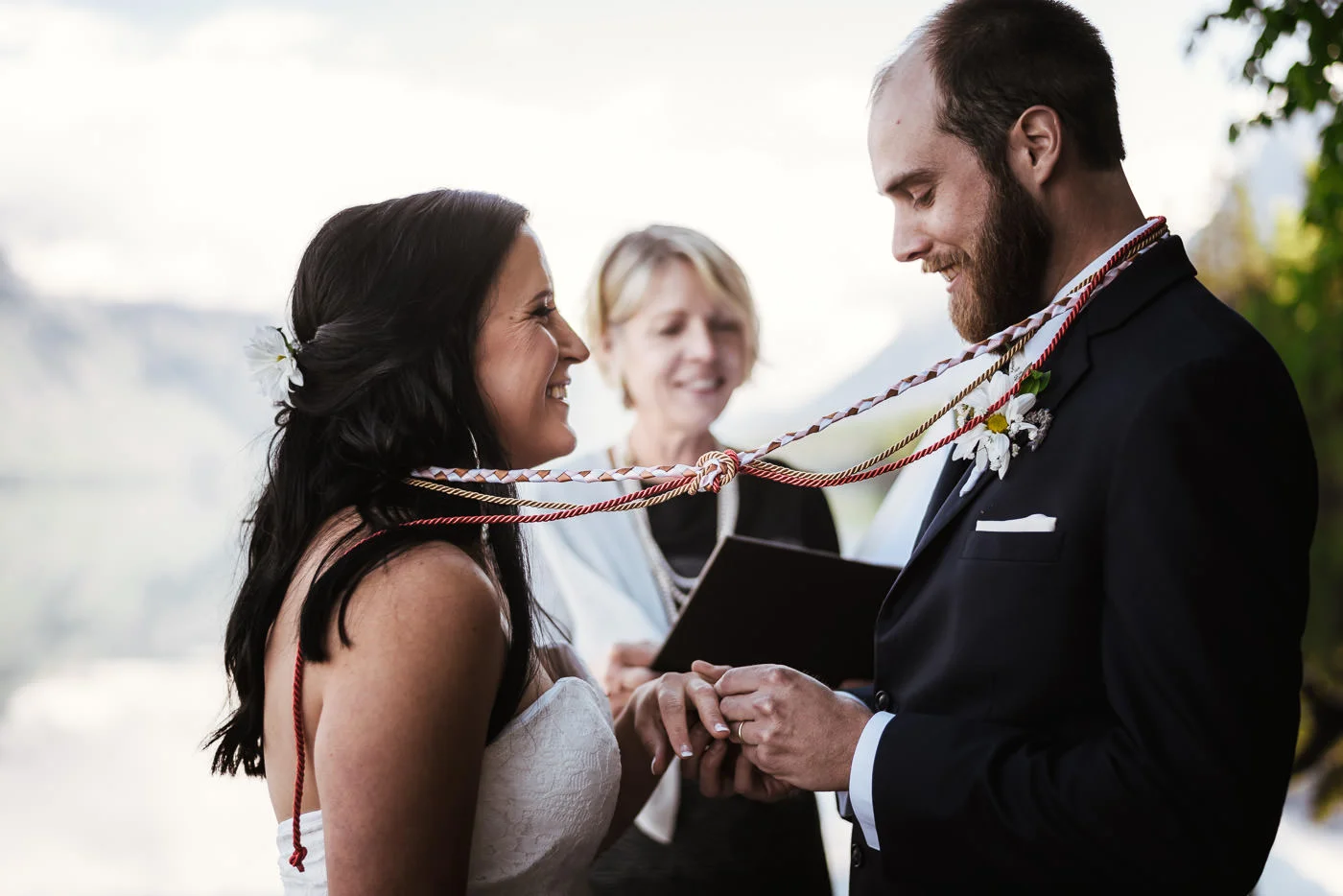 Bride and groom smile as the ring is placed on the finger.