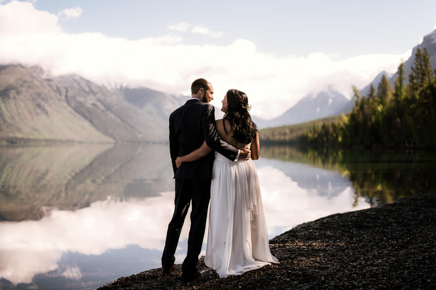 Newly married couple savors a moment alone on the shore of Lake Mcdonald after their Glacier National Park Elopement.