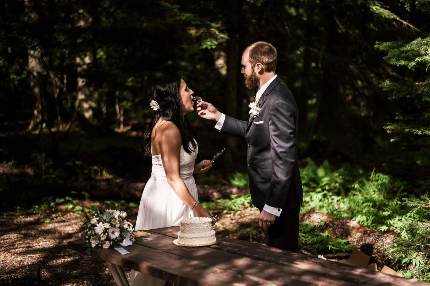 Husband feeds his new wife a piece of cake at their Montana wedding.