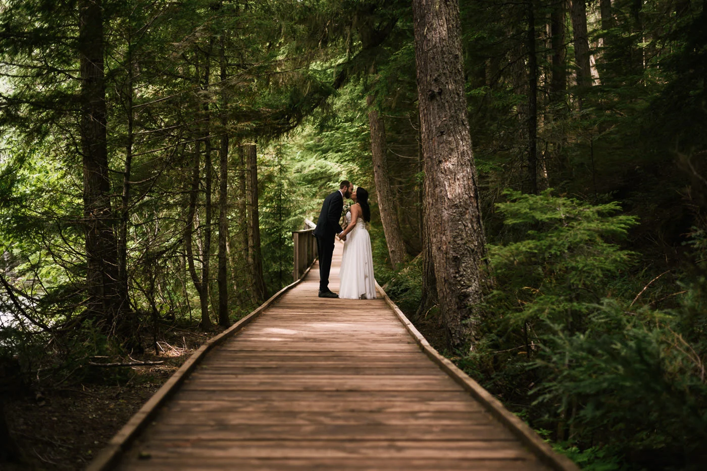 Couples stops for a kiss while hiking the trail of cedars in Montana.