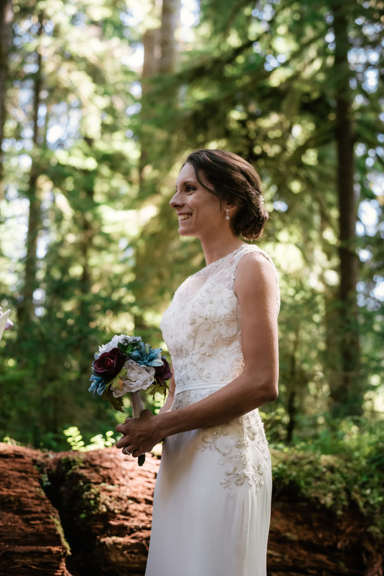 Bride smiles at her groom as he reads his wedding vows in the Hoh Rainforest.
