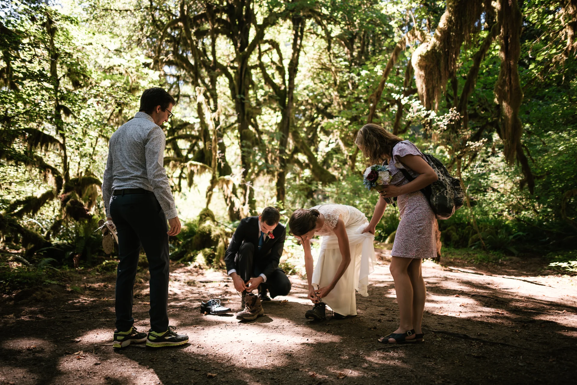 Couple pauses for a moment to switch their shoes for a short hike in their wedding attire.
