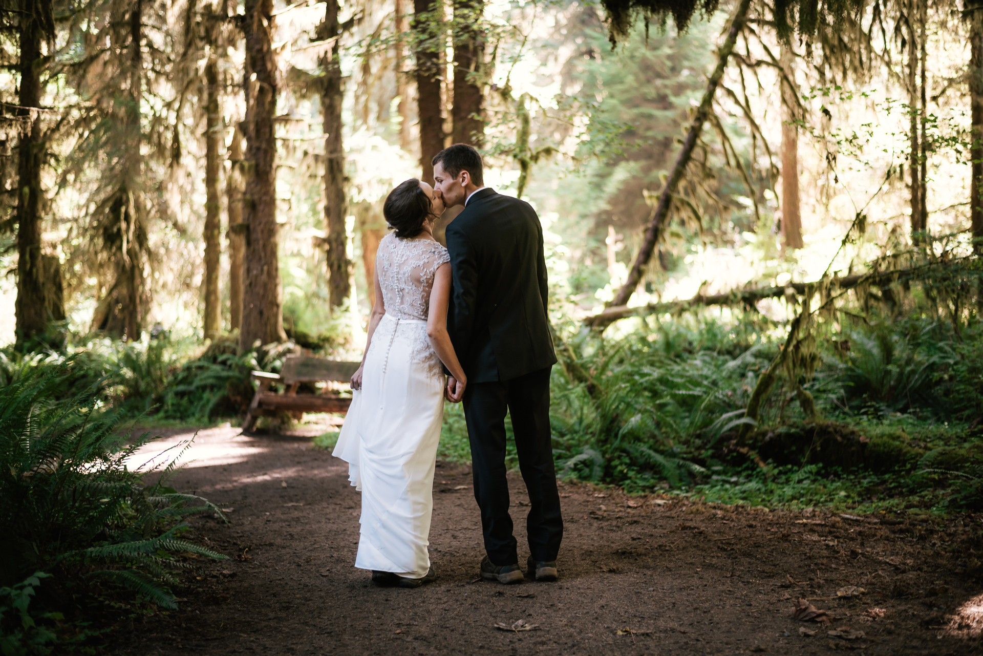 Eloping couple stops for a kiss during their hike through the Hoh Rainforest.