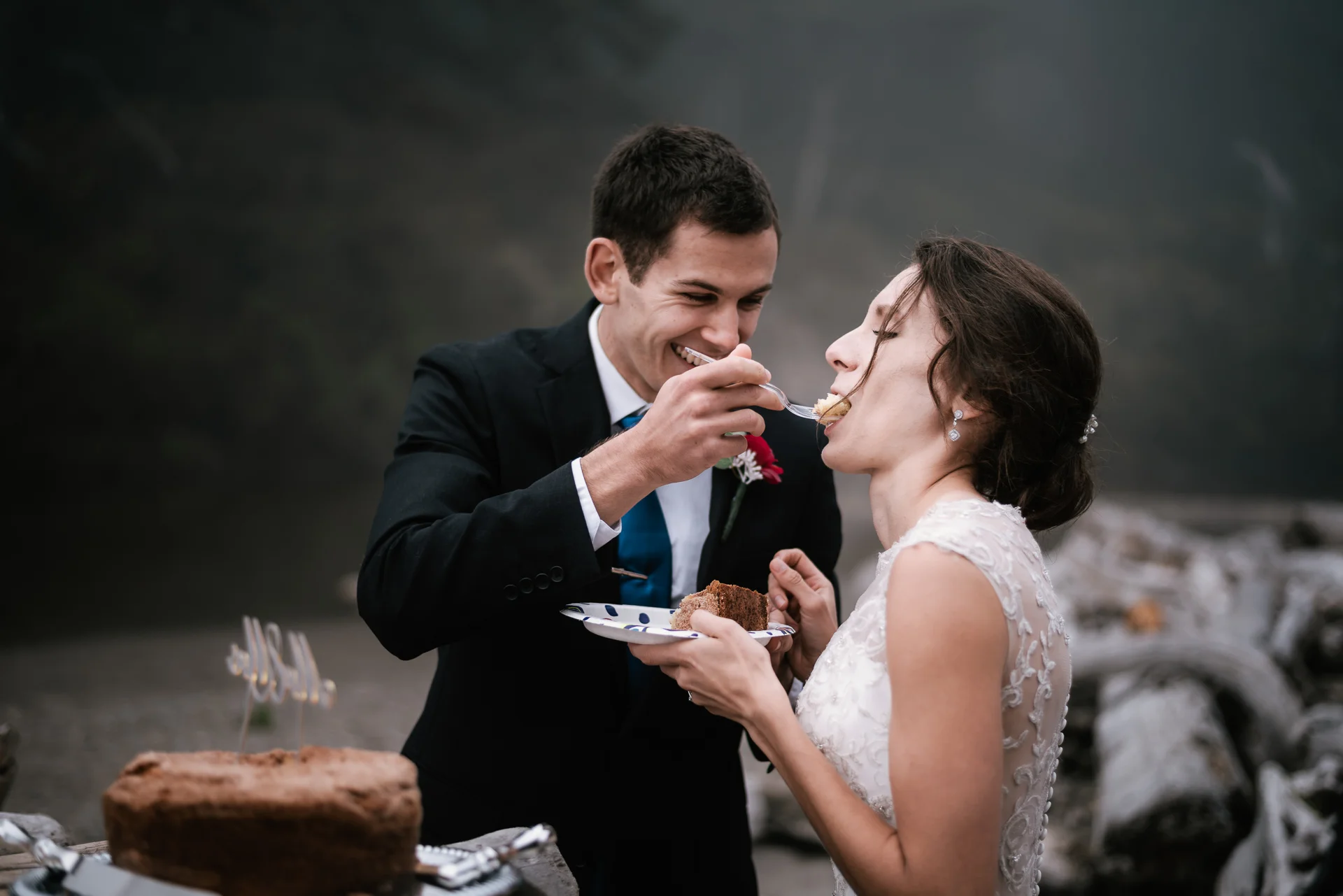 Groom gives his new wife a big bite of wedding cake.