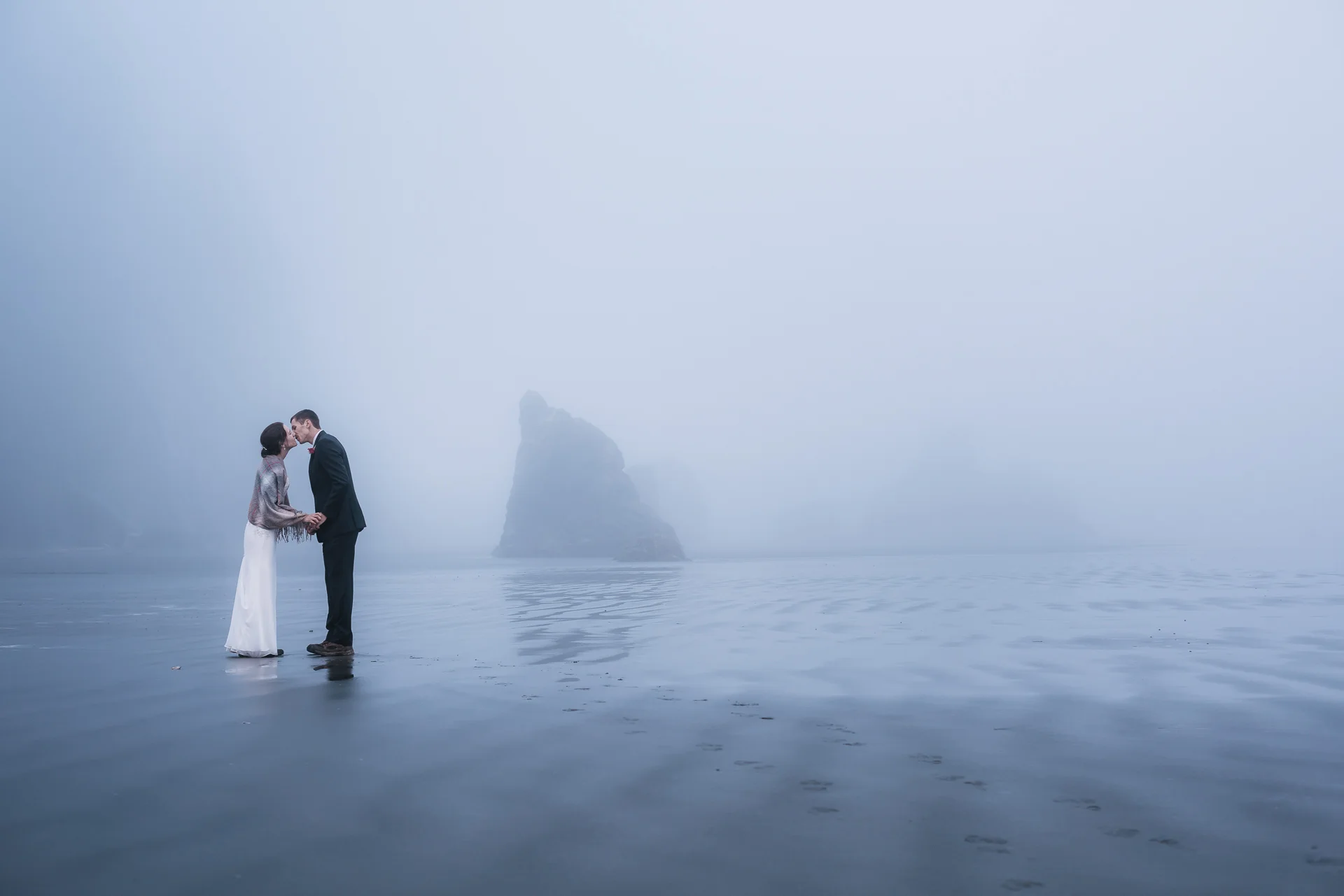 Wet sand and fog make a perfect backdrop for romantic wedding photos on the Washington coast.