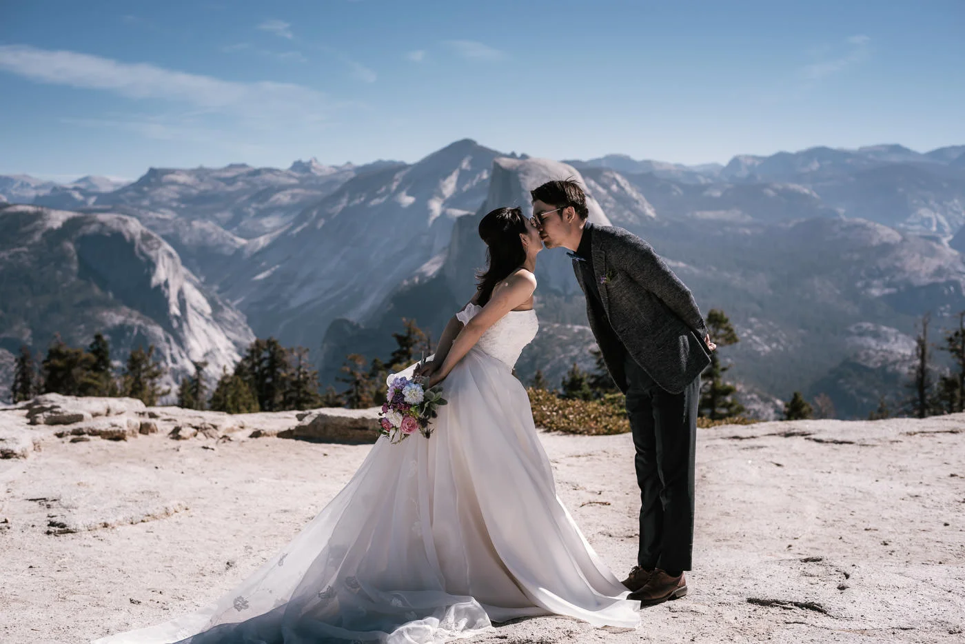 Bride and groom lean in togeather for a sweet kiss with the sprawling vista of the Sierra in the background.