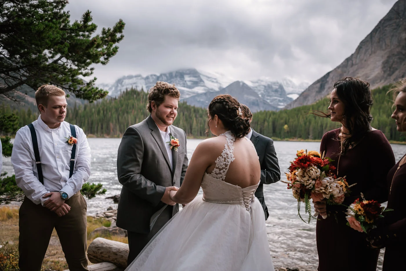 Groom smiles at his bride as they exchange their vows in Glacier National Park.