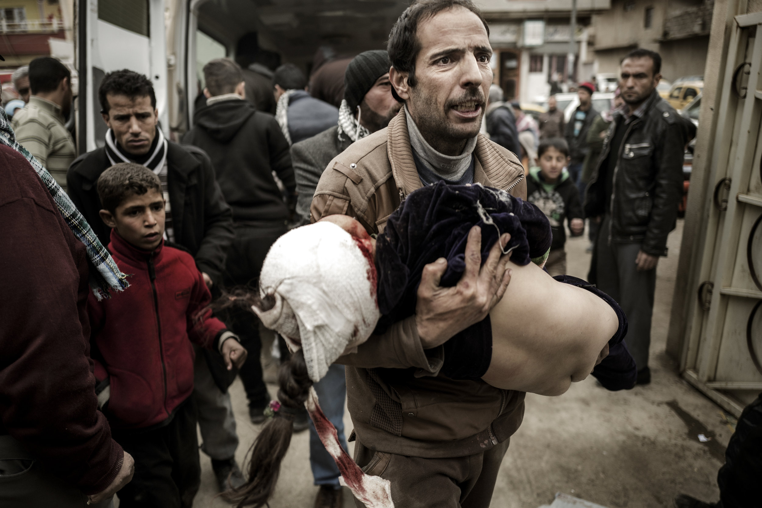  Mohammad jumps out of one of the two ambulances filled with wounded children, that has just pulled up in front of the field hospital. He’s carrying his daughter Ghufran in his arms. Half an hour earlier the ten year old girl was playing with her sib