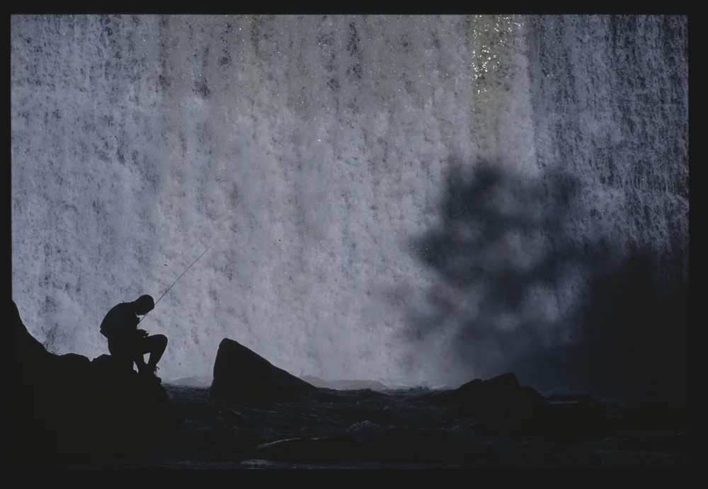 fly fishing near a waterfall