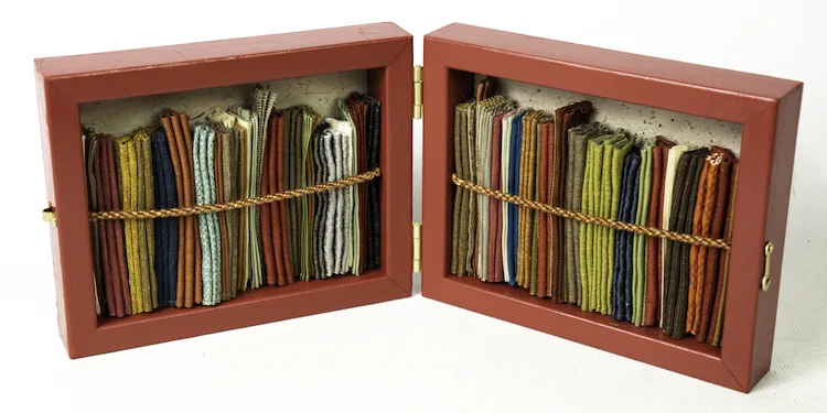 What’s the Title? 20”x8”x3.5” (open) design samples (wool, silk, linen, et al.) folded and stitched by machine and hand; frange torse; painted wood shadow boxes lined with handmade paper ( India and Japan); metal hinges and closure
