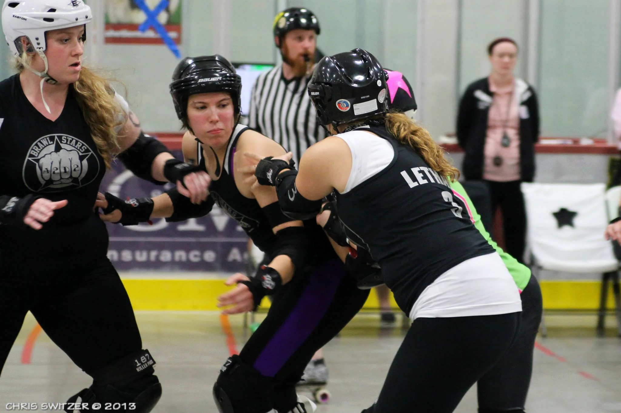 Slamlet is flanked by Brawlstars teammates Courtnasty (left) and Lethal Bo Peep (right) as they block Lansing's jammer during the championship game of the Mitten Kitten Mash-Up North tournament in Kalkaska October 13, 2013. Ultimately, the Brawlstars reigned victorious 256-151. Photo by Chris Switzer.