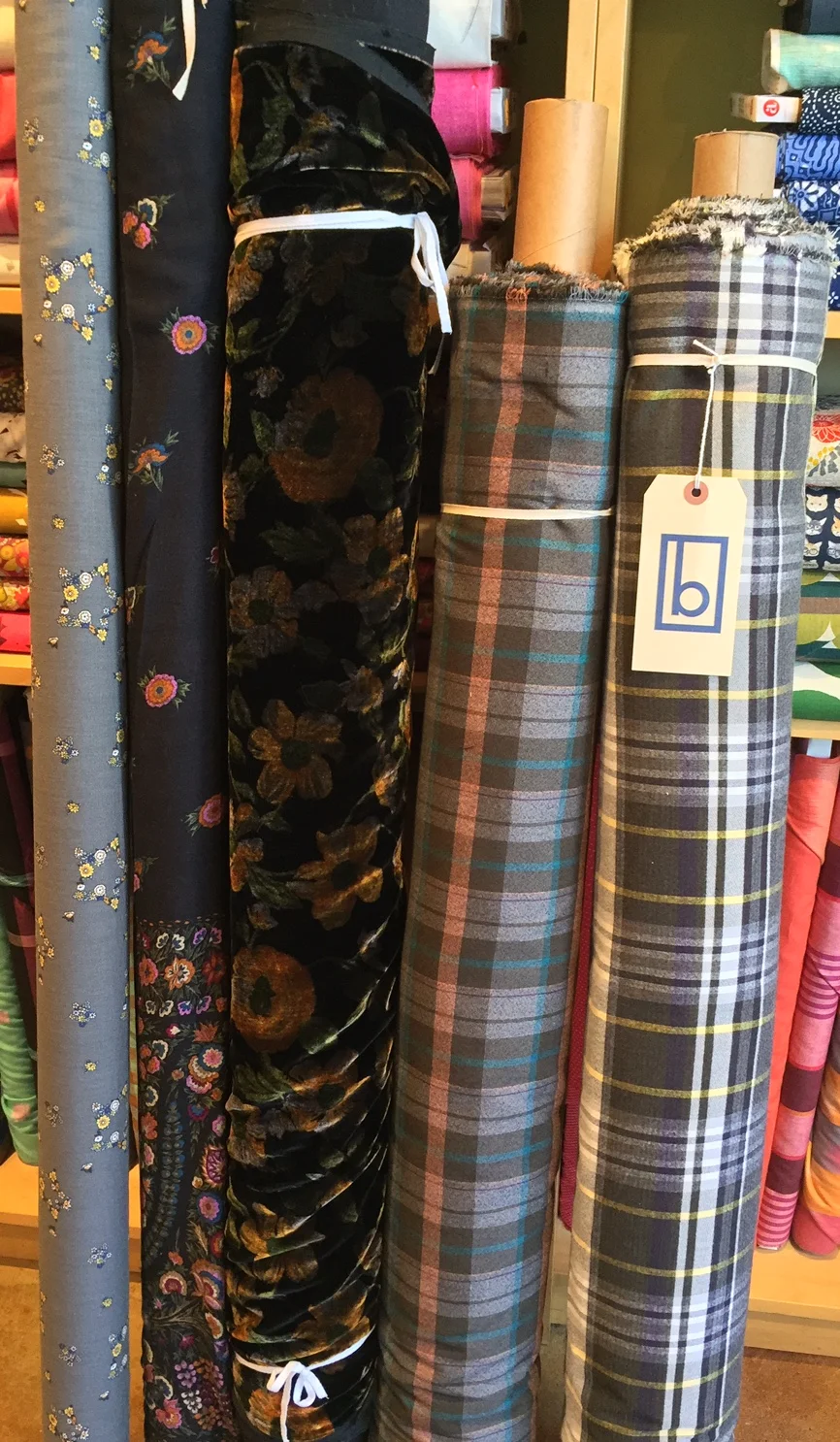 This group offers quite the combination of goodies. On the far left are two very lovely wool/rayon blend prints. These have a beautiful, fluid drape to them. The rayon/ silk velvet in the middle shows off its stunning golden flowers in just the right light, and the two cotton blend plaids are the perfect winter button-up! Check out the Thread Theory patterns on our online store for the Fairfield!