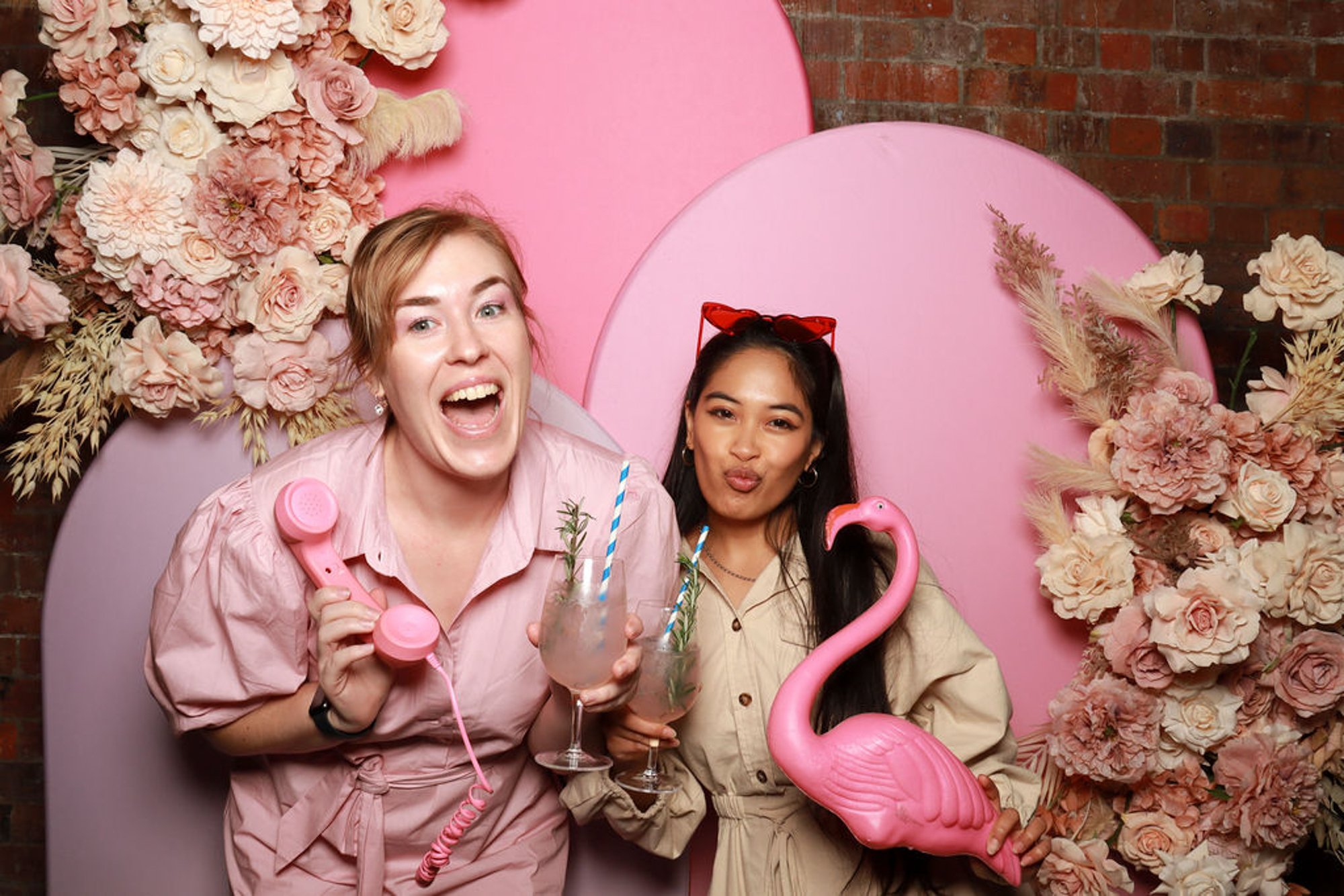 Guests celebrating against layered pink arches styled with statement florals and playful props.