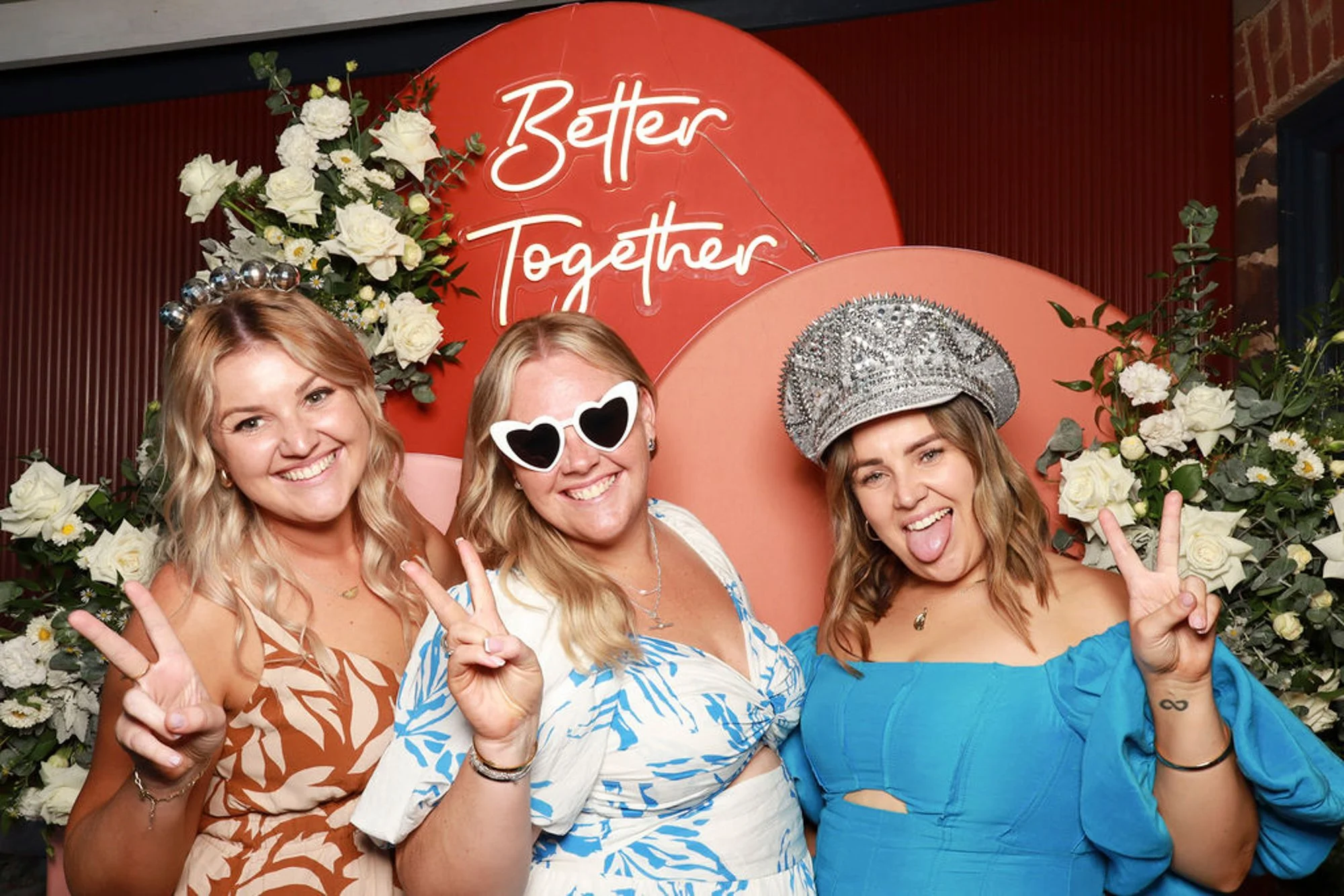 Guests posing in front of warm sculptural arches styled with statement florals for a luxe event backdrop.