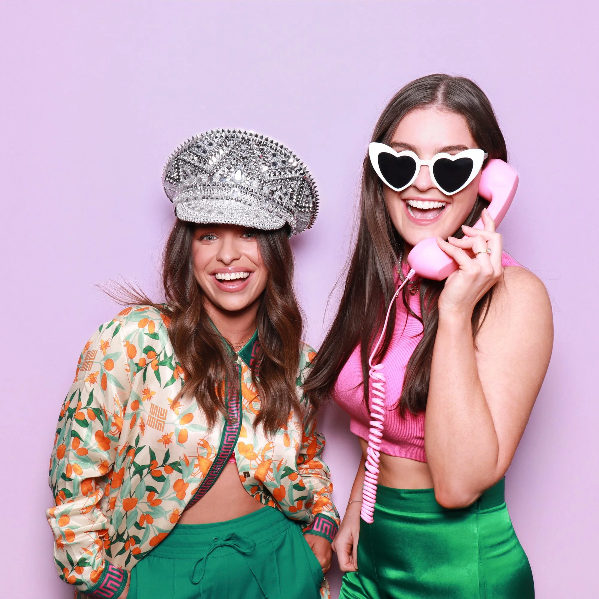 Wedding guests posing with a retro phone and statement sunglasses in a stylish photo booth.