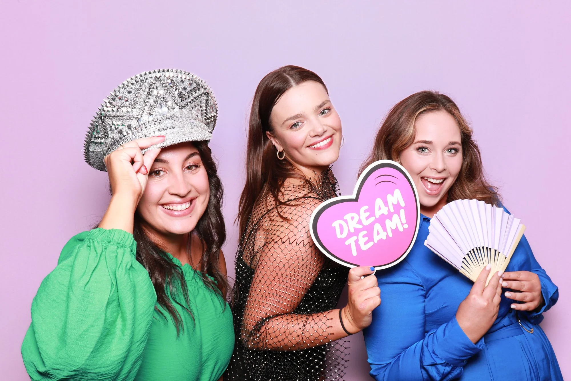 Group of colleagues posing with a Dream Team sign and hand fan in a Photo Corner photo booth.