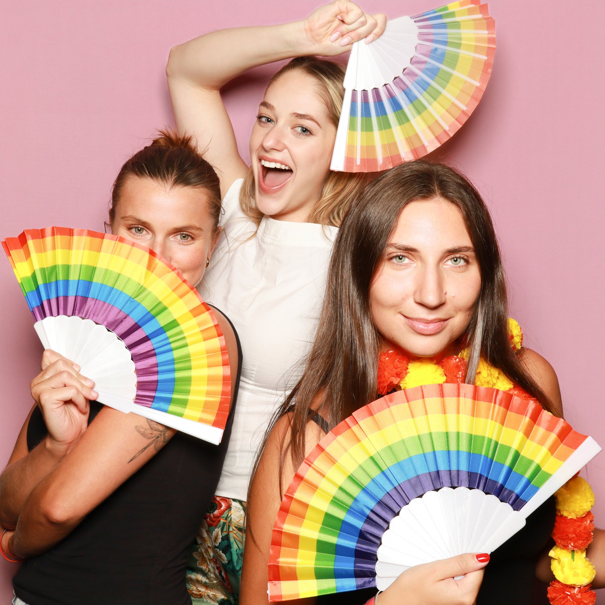 Guests celebrating Pride with rainbow fans and colourful photo booth props.