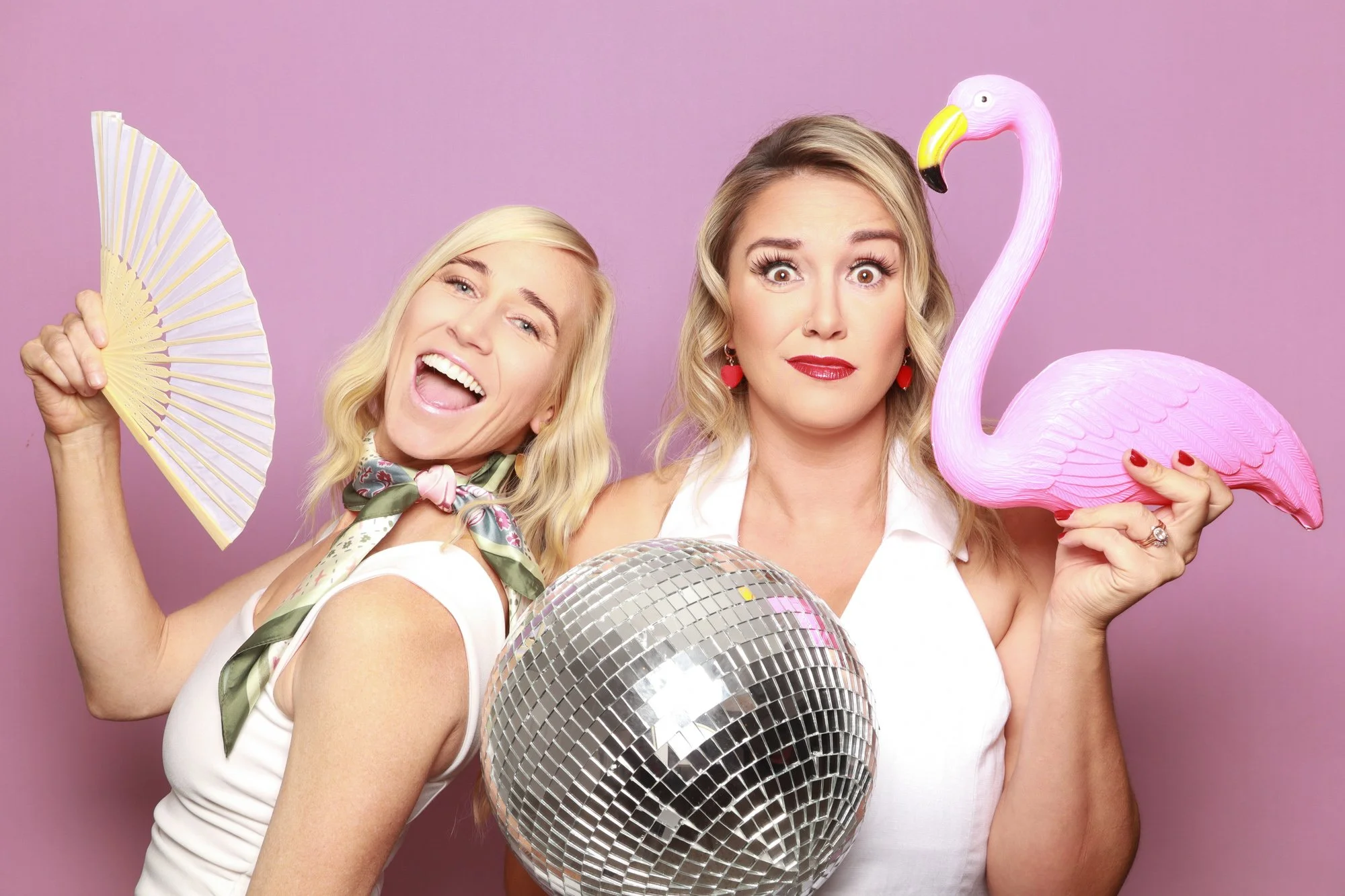 Guests posing with a flamingo, disco ball and hand fan in a Photo Corner photo booth.