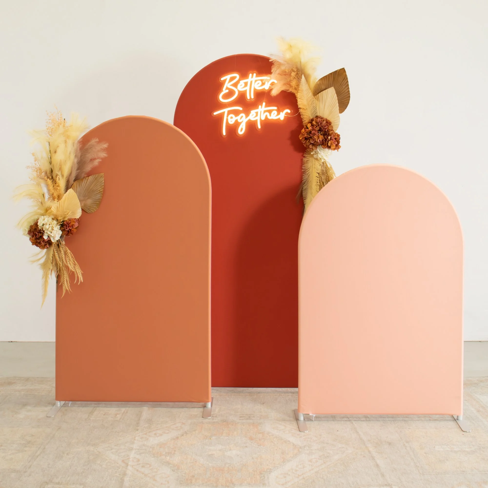 Sand Dune Arches luxe photo booth backdrop in warm terracotta and blush tones, styled with dried florals and a Better Together neon sign.