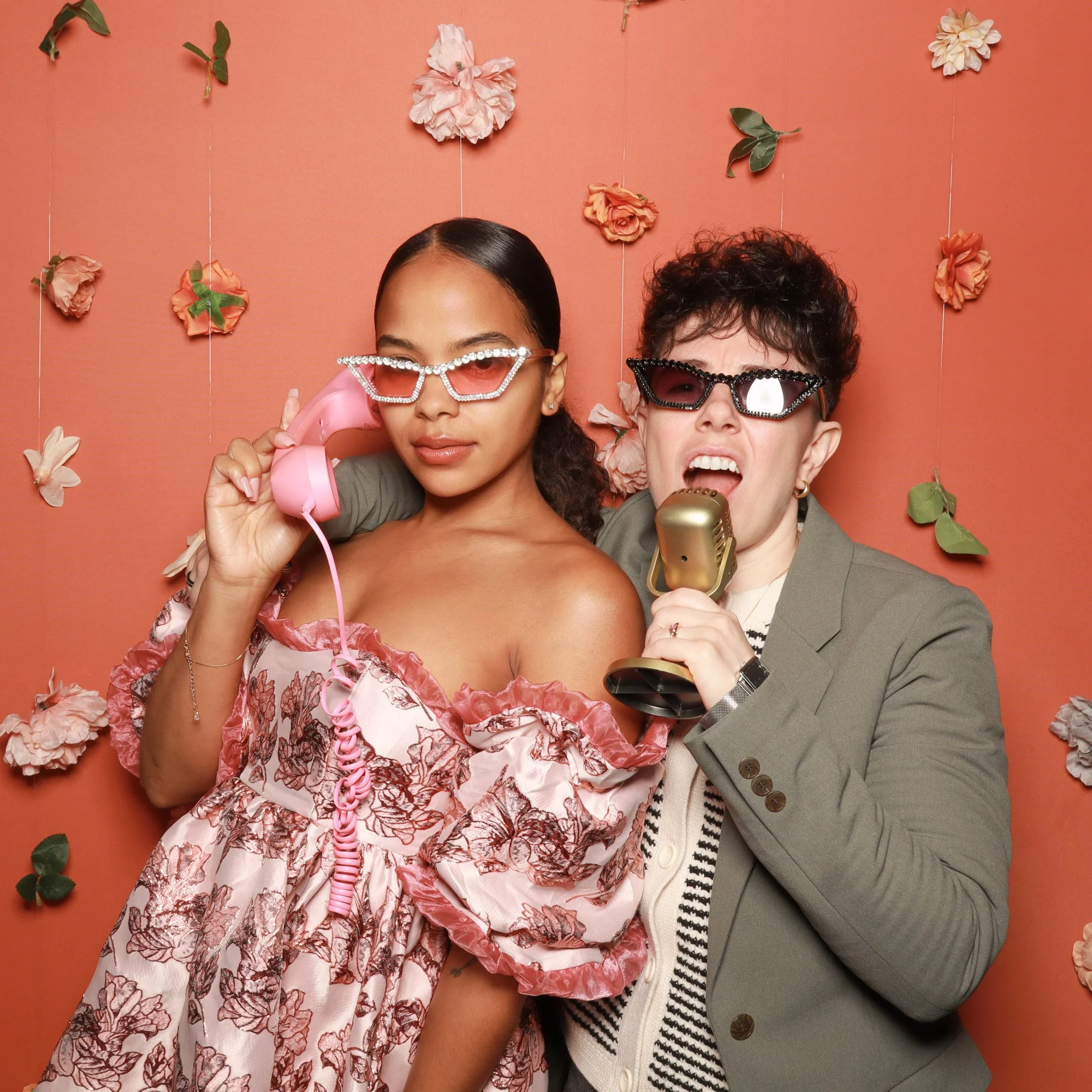 Guests posing with retro phone and microphone props at a stylish wedding photo booth.