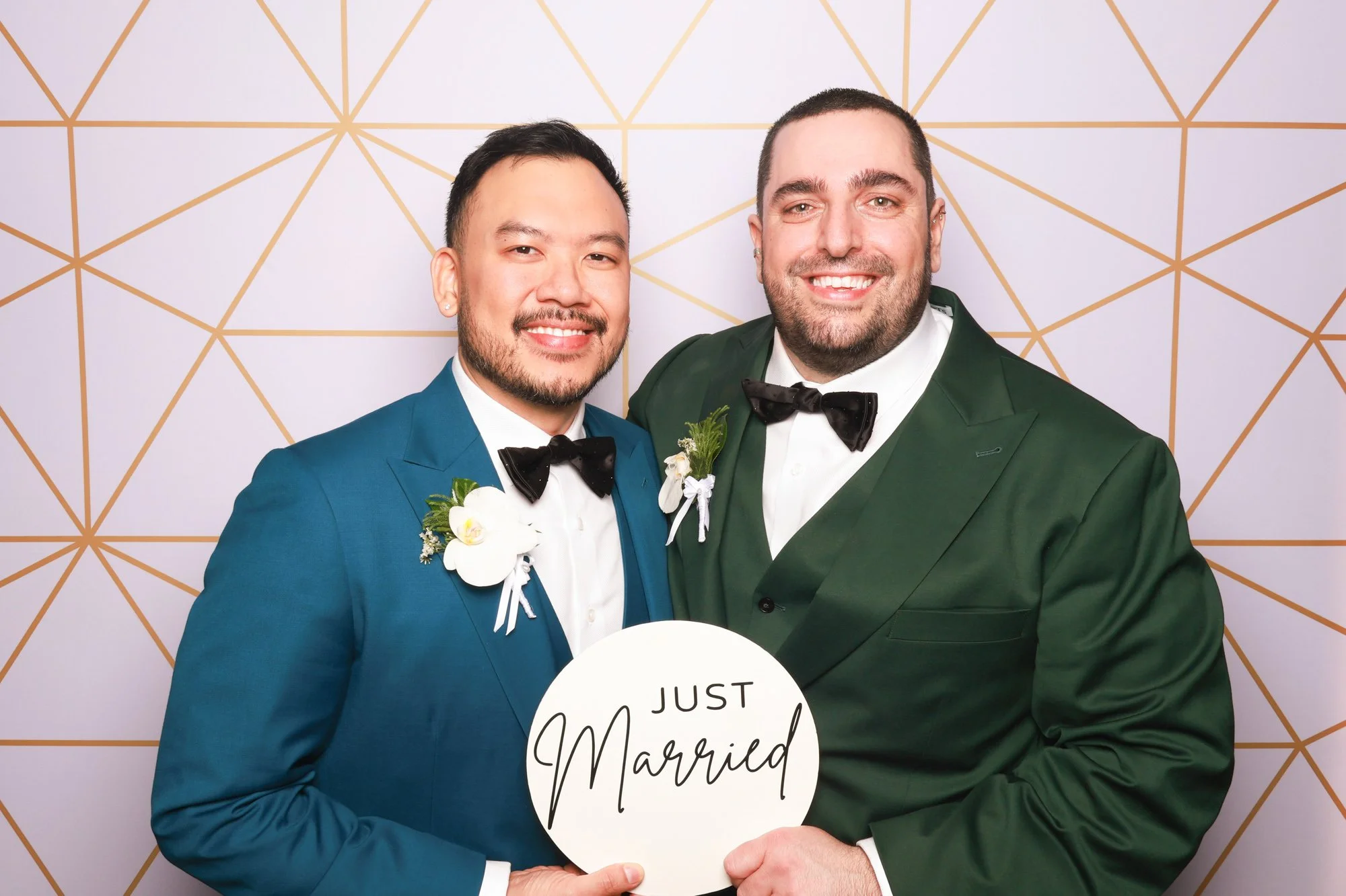 Same-sex couple posing with Just Married sign at wedding photo booth in Sydney.