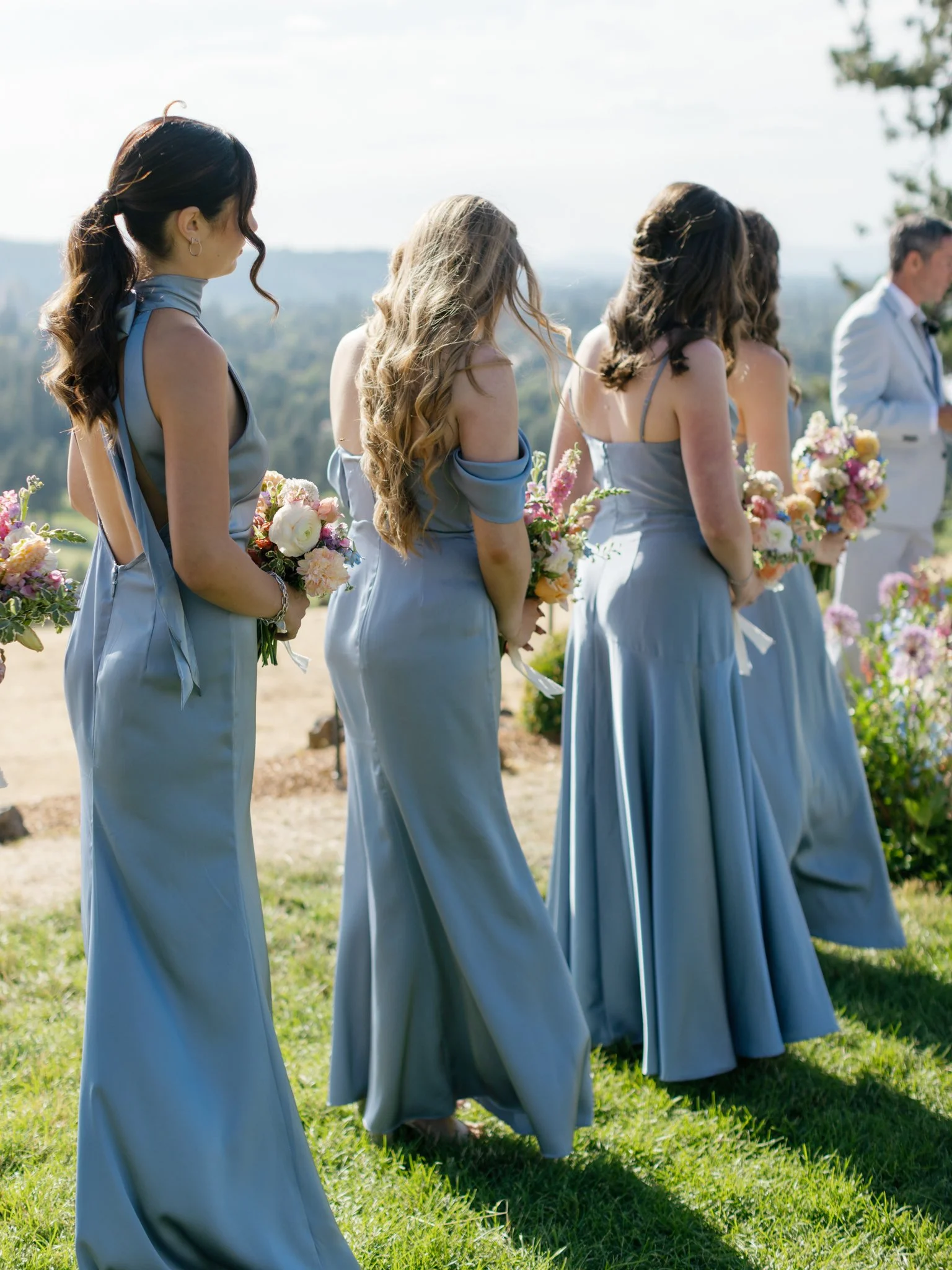 Bridesmaids in matching light blue dresses holding flowers during outdoor wedding ceremony at Elk Point mountaintop wedding.