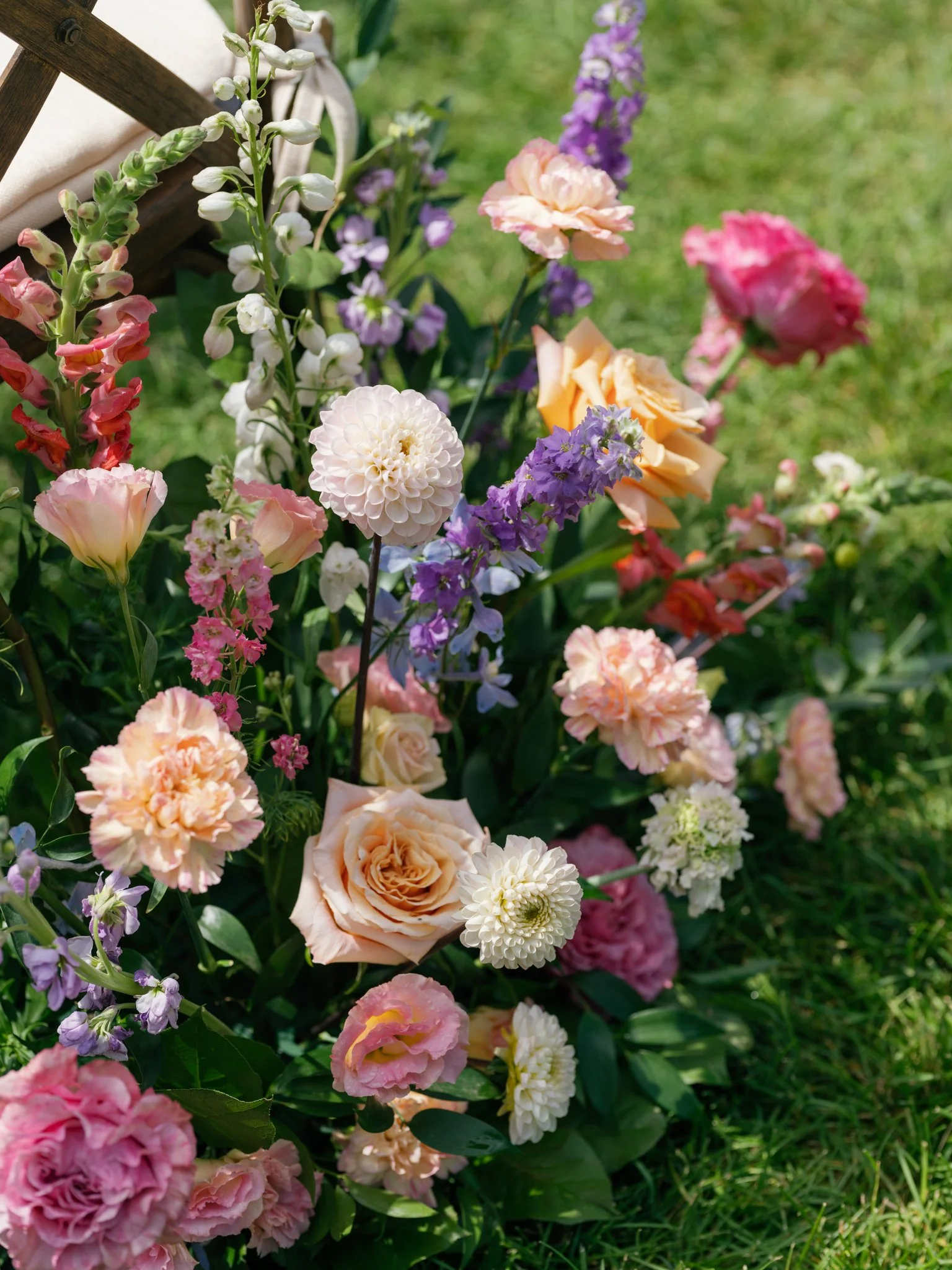 Colorful flower arrangement with pink, peach, and purple flowers on grass at Elk Point wedding above Lake Coeur d’Alene.