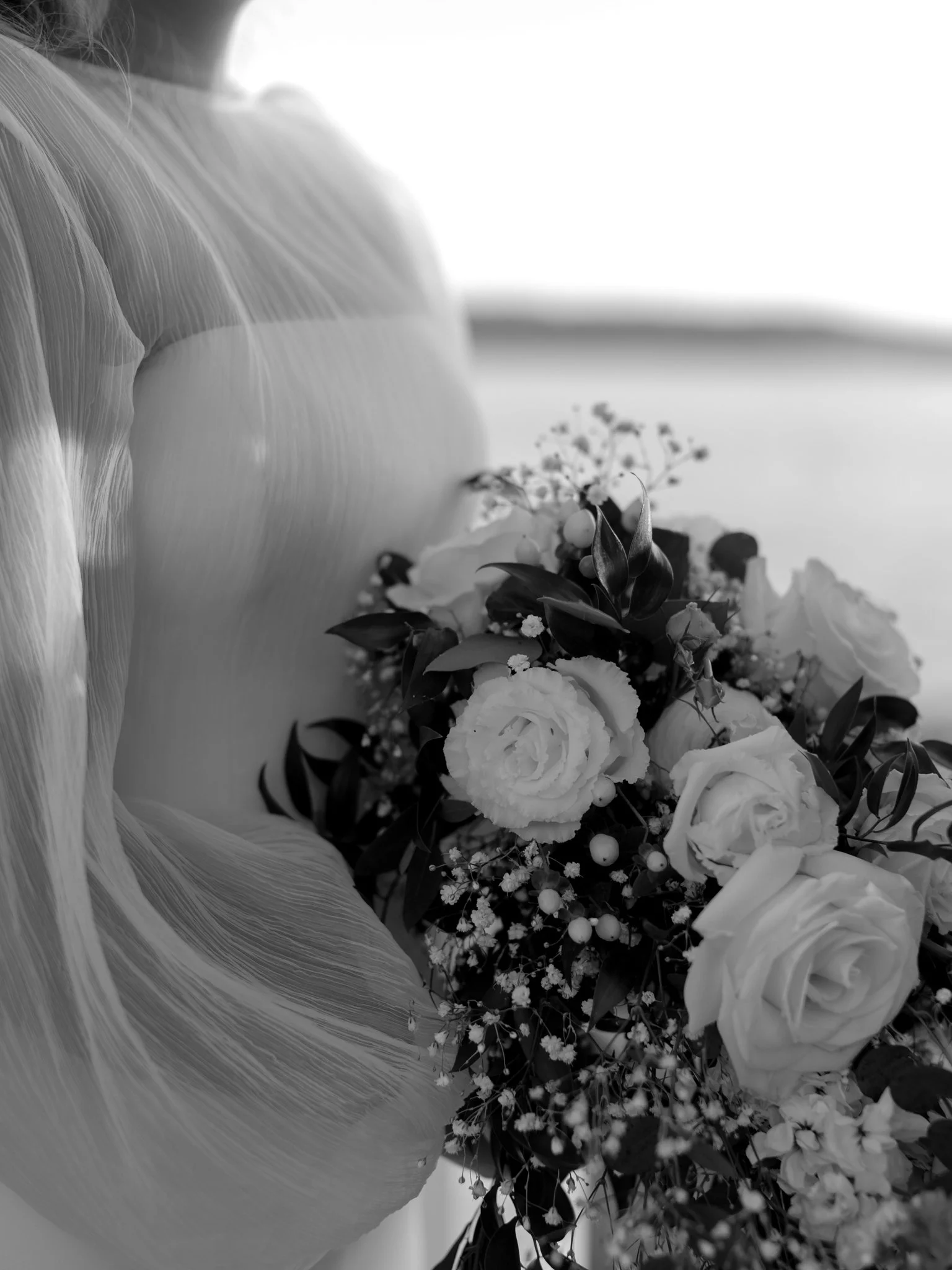 Black and white photo of a bouquet of roses and other flowers next to a textured wedding dress at the Hagadone Event Center in Coeur d'Alene, Idaho.