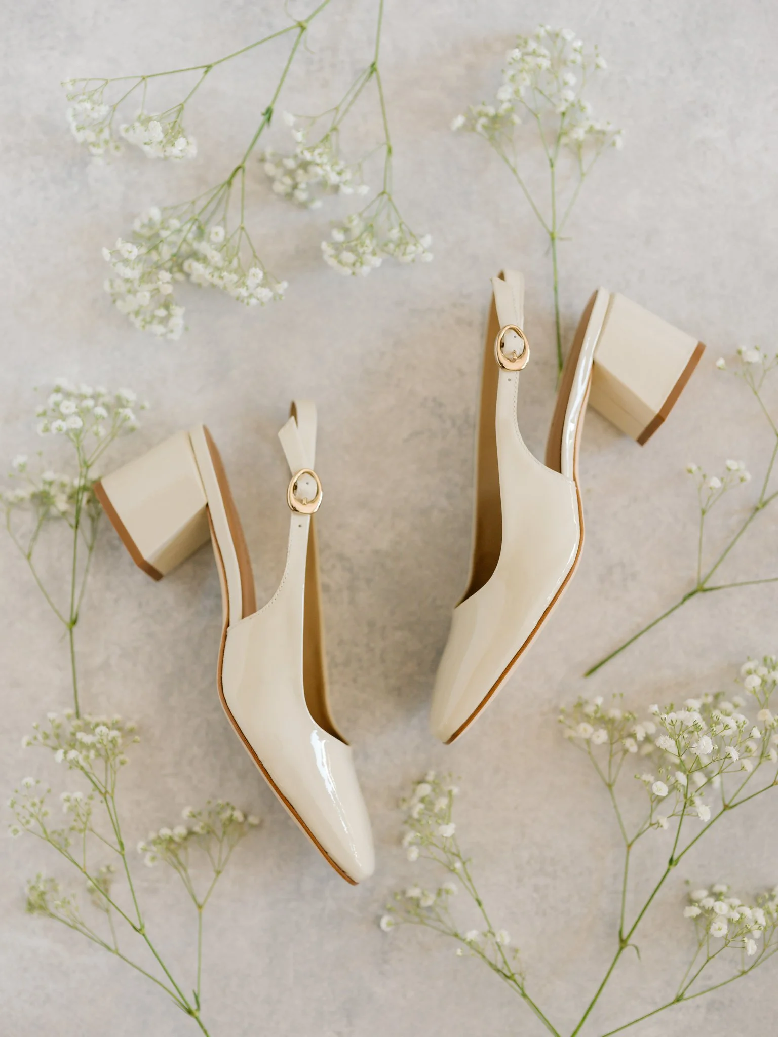 Editorial flatlay of ivory bridal heels surrounded by baby’s breath flowers for a summer wedding in Coeur d’Alene.