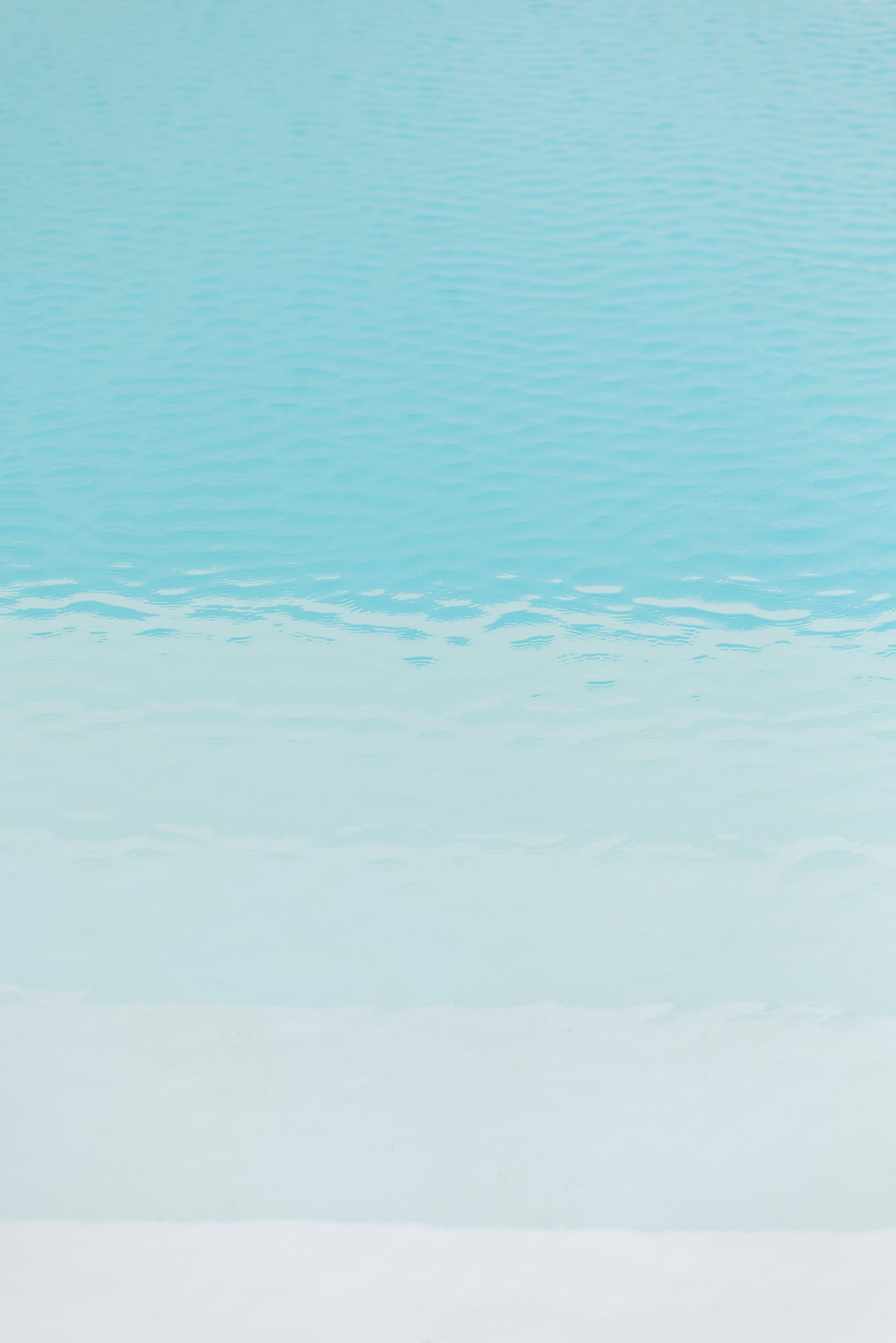 Calm ocean water with gentle ripples under a light blue sky.