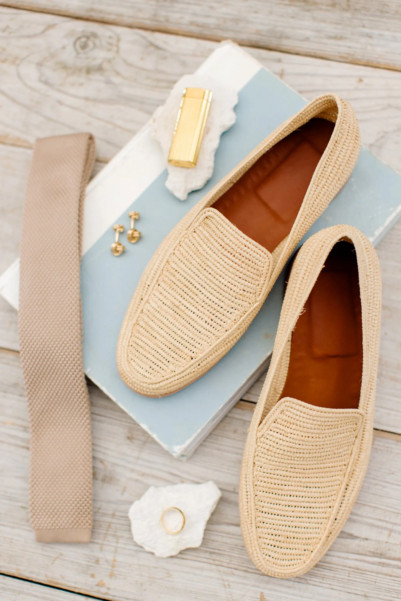 Beige woven loafers shoes with gold jewelry and accessories on a rustic wooden surface at The Other Side Hotel Eleuthera during a luxury Bahamas destination wedding.