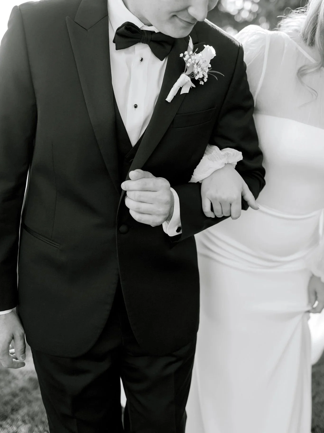 Close-up black and white photo of the groom walking arm-in-arm with the bride during their lakeside wedding at the Hagadone Event Center in Coeur d’Alene.